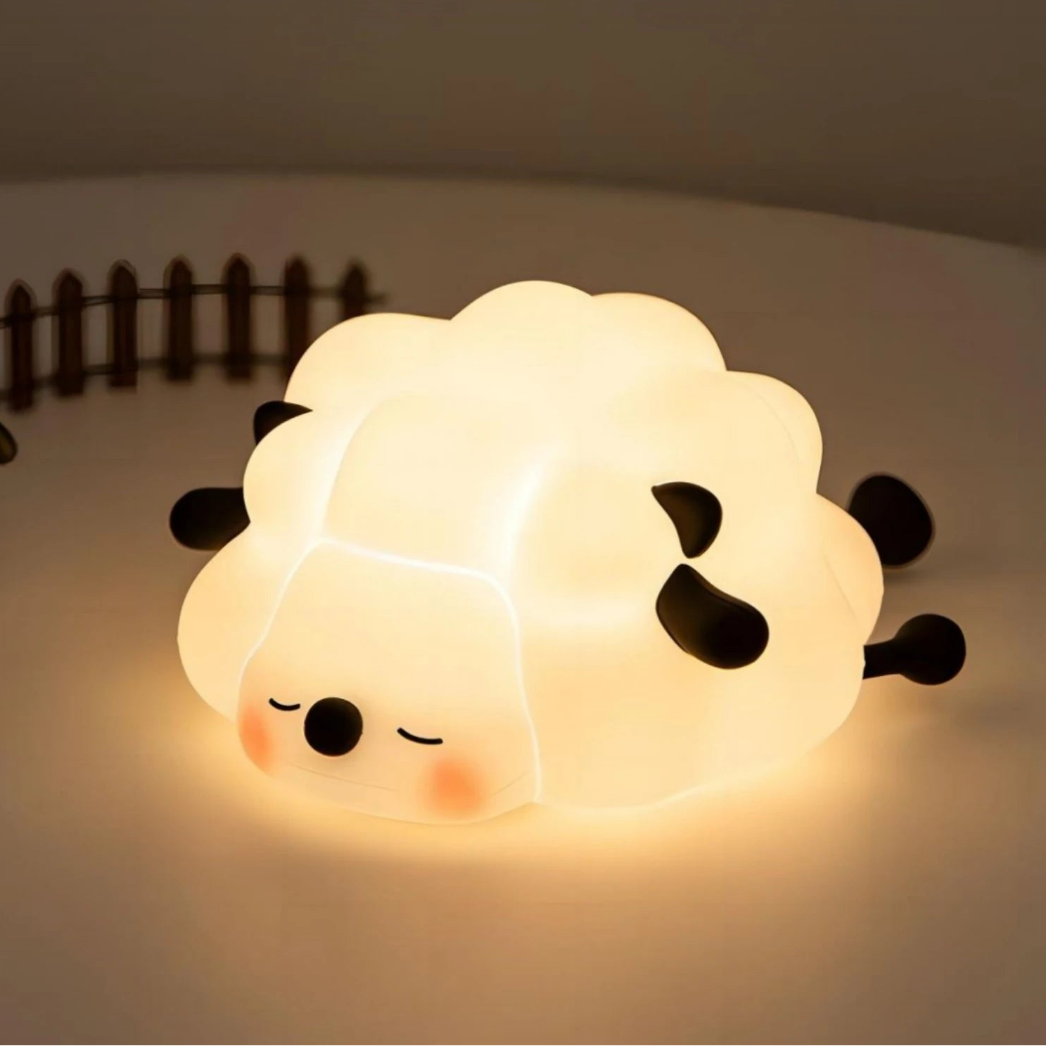Sheep-shaped night light emitting a warm glow on a neutral background