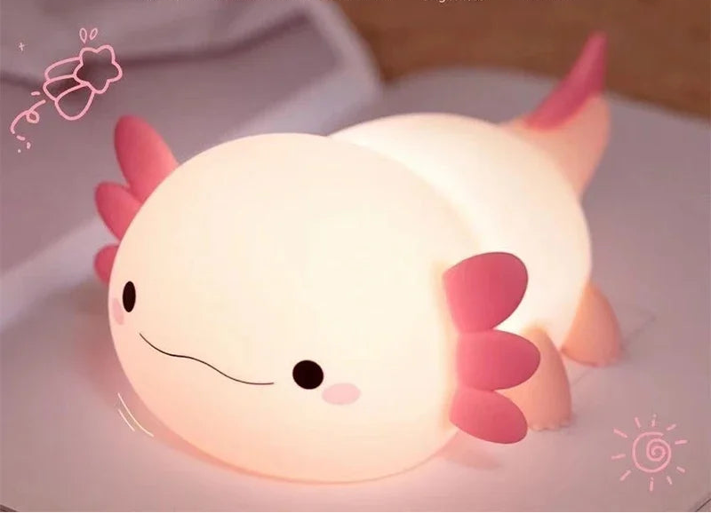 Axolotl-shaped night light with pink accents on a white surface, featuring text about its features.